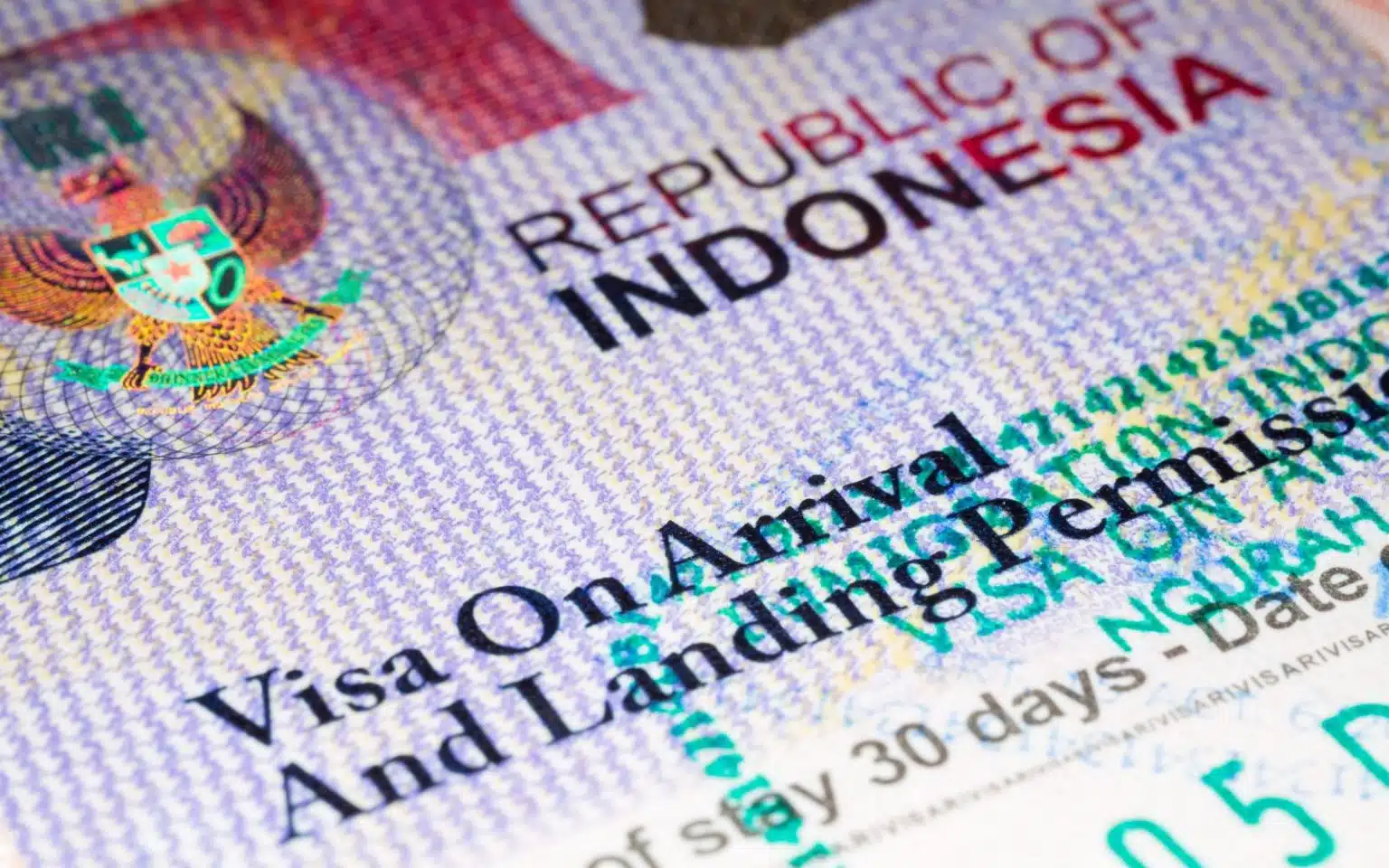 Close-up of an Indonesian visa in a passport. The text on the visa reads "Visa On Arrival and Landing Permission" and indicates a stay of 30 days. The background shows intricate security patterns and the emblem of the Republic of Indonesia.